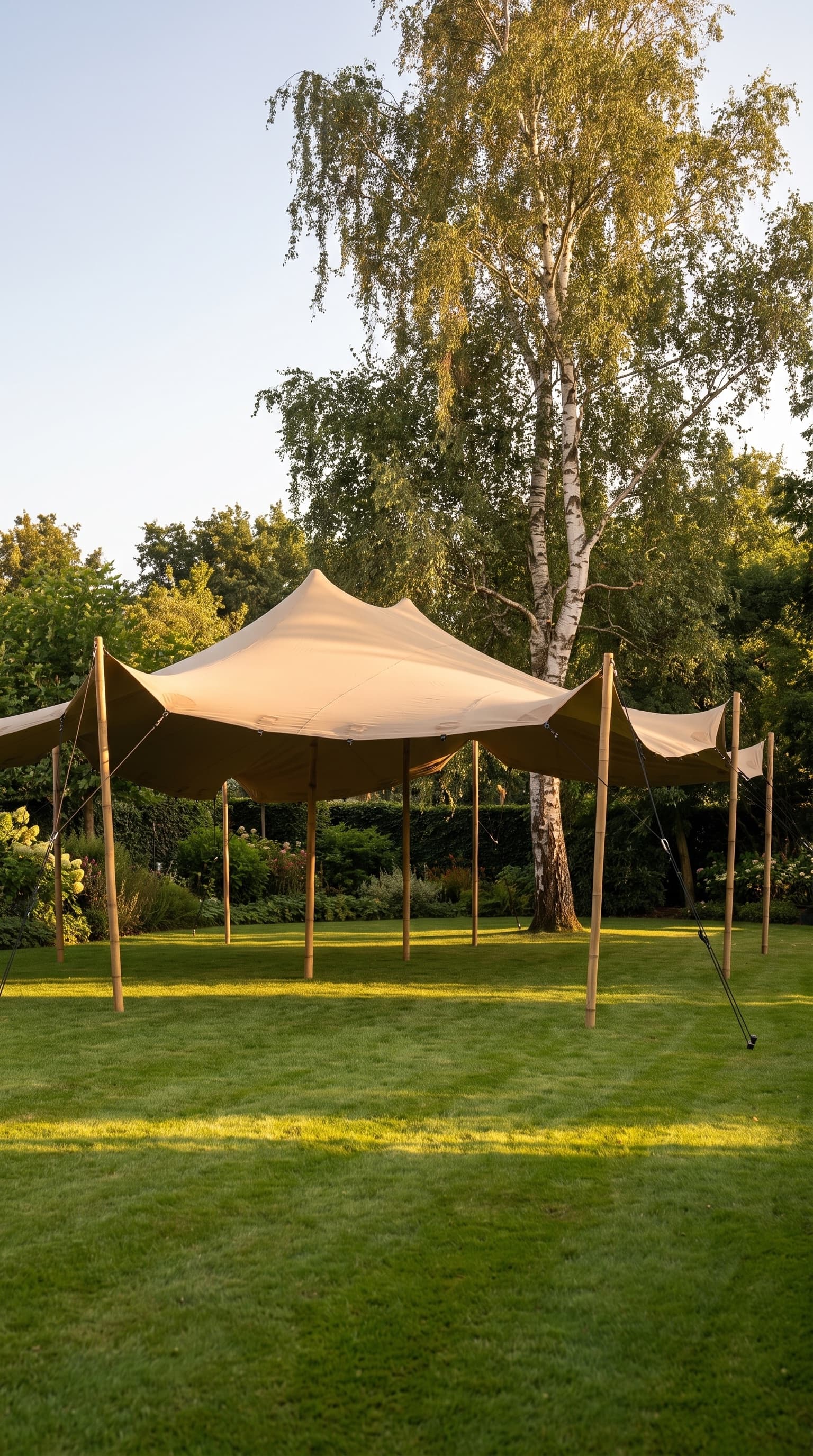 Sand-kleurige stretchtent in een groene tuin bij avondlicht